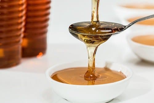 Honey pouring from a spoon into a bowl