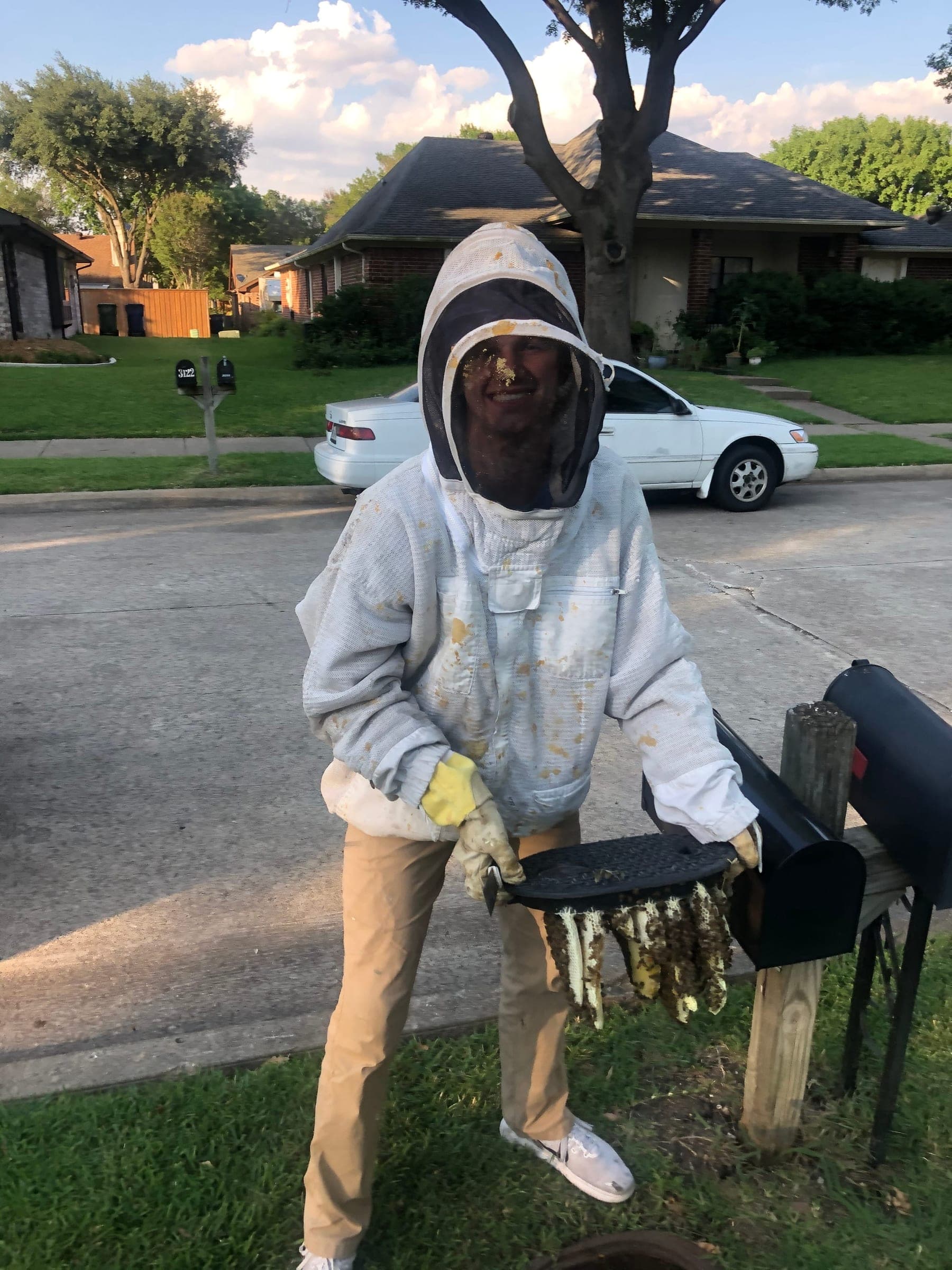 A beekeeper holding a frame of salvaged comb after a removal