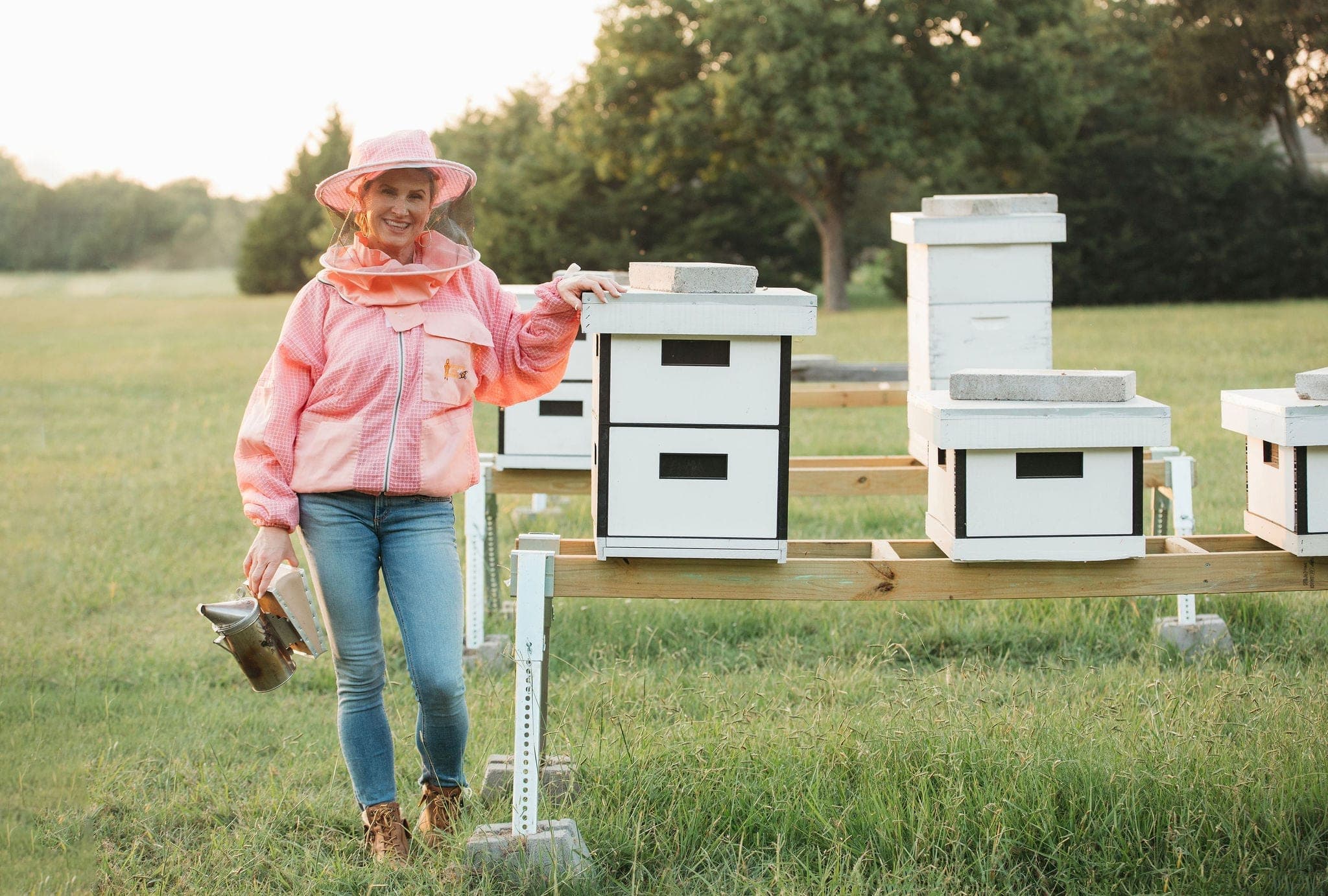 A beekeeper in the apiary beside a row of hives